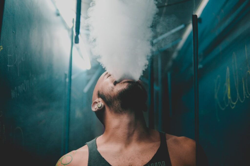 Crafting Captivating Headlines: Your awesome post title goes here A bearded man in a tank top exhales smoke in a moody indoor environment.